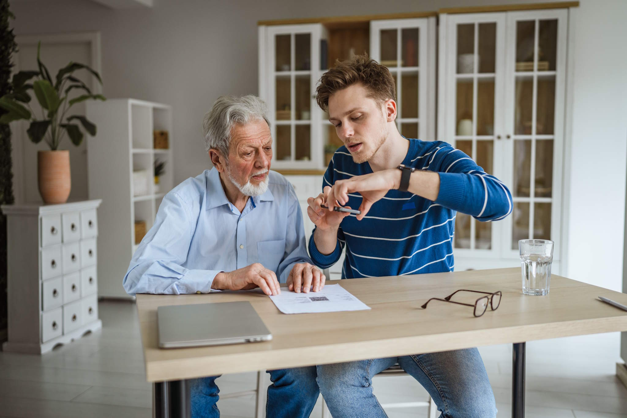 Junge Person unterstützt alte Person beim Einscannen eines Dokuments